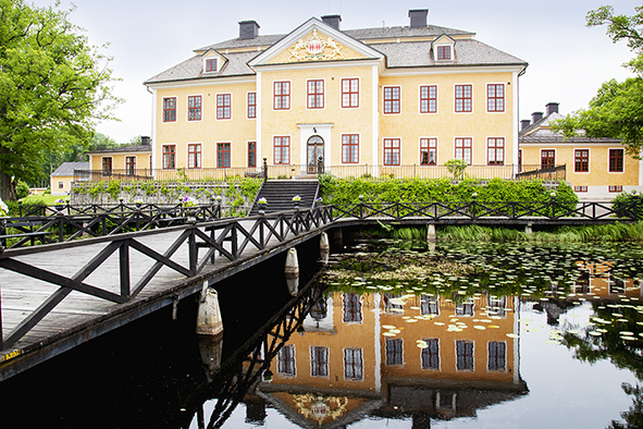 Herrgården i Lövsta bruk omgiven av vattnet och övriga bruksmiljön. 