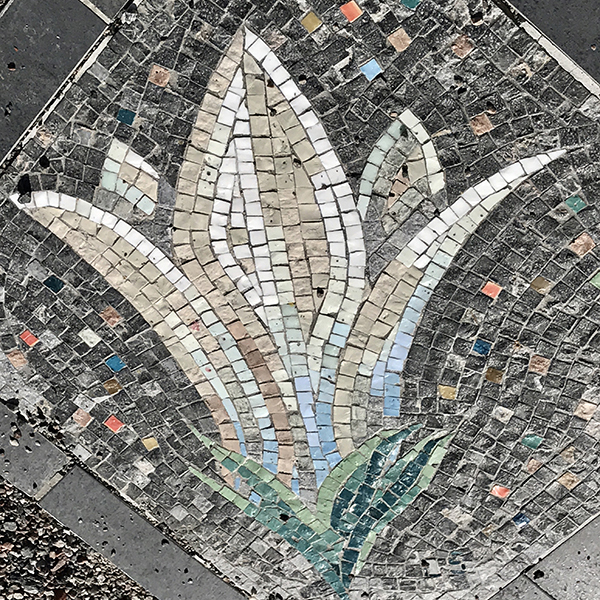 Mosaik föreställande klockformig blomma. Konstnär Liv Saetre.