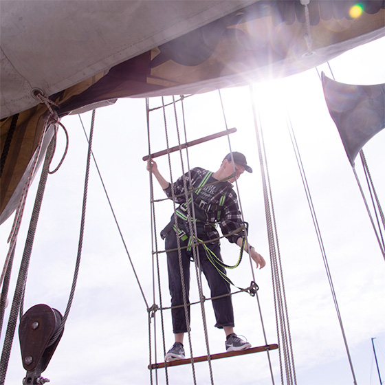 A person climbing the sails of a ship