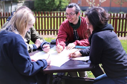 Bild på personer som jobbar tillsammans vid ett bord utomhus