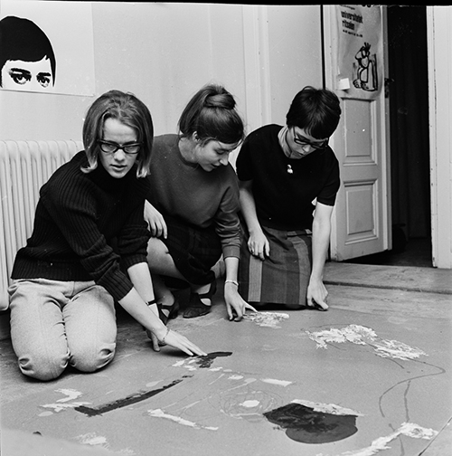 Tre kvinnor sitter på golv, svartvit bild.