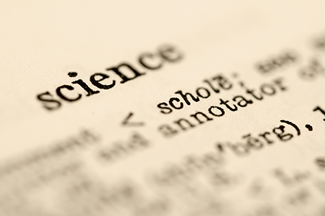 Ordet "science" inzoomat med kort skärpedjup i en ordbok med gulnat papper. 
