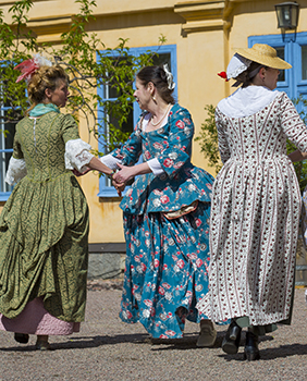 Tre dansande damer i 1700-talsdräkter