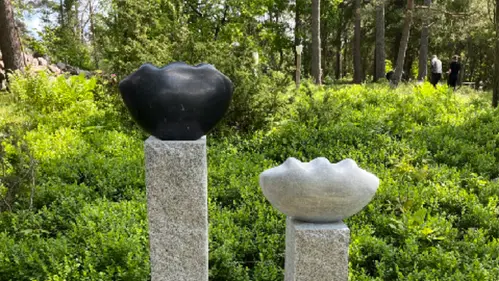 två skulpturer i svart och vit polerad sten uppställda på varsin granitstolpe. Skulpturen Tankefrön av Kerstin Dahl Norén.