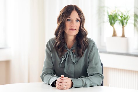 Therese Pettersson wearing a green tie blouse, sitting at a table.