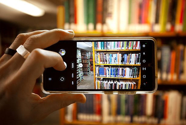 Bokhyllor med böcker sedda genom en mobilkamera