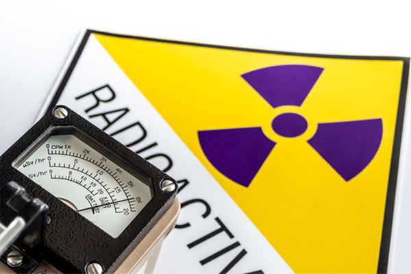 En geigermätare framför en skylt med radioaktivitetssymbol.