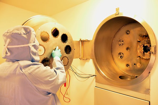 Final station of the implantation beamline. A man in protective gear is installing wafers.