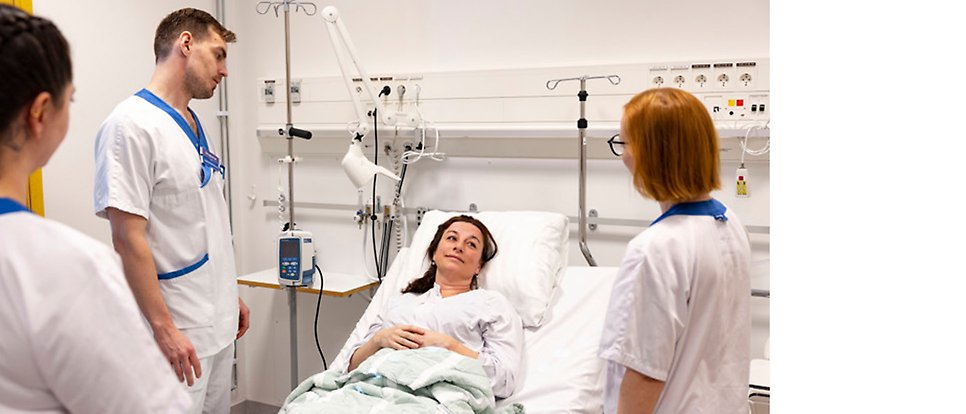 Sjukskötesstudenter som står kring en sjuksäng med en patient 