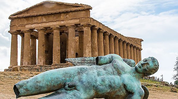 En avbruten grekisk staty framför ett grekiskt tempel med höga kolonner