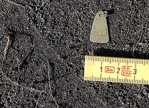 En tumstock mäter ett metallföremål på marken