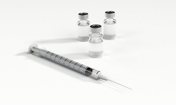 Bild på en vaccinationsspruta och ampuller med vaccin
