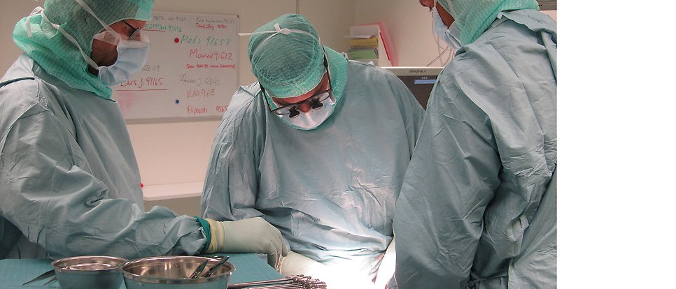 Operation med tre operatörer i operationskläder