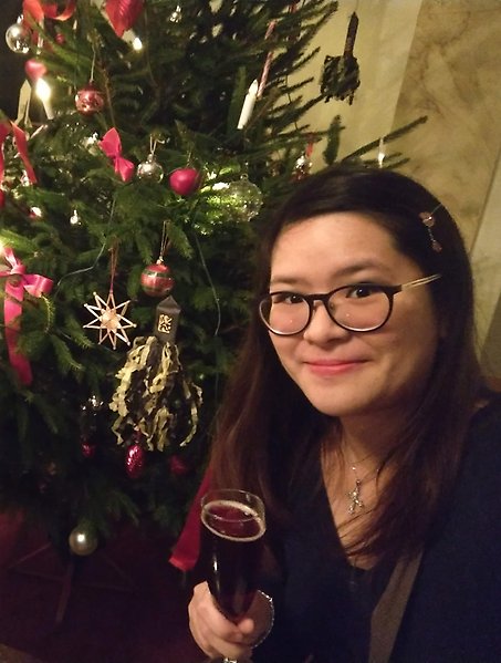 Jessie i glasögon framför en julgran med pynt