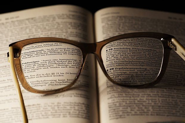 Bild av glasögon ovanpå en uppslagen bok.