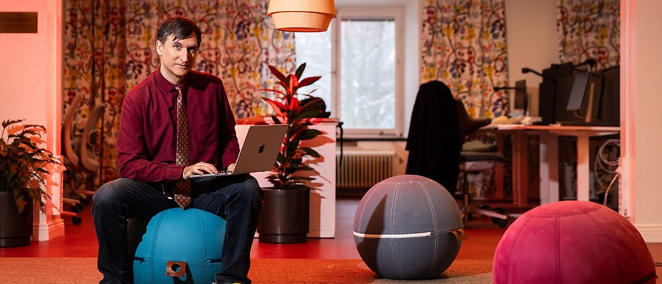 Matteo Magnani sits with the laptop in his lap on a bean bag chair shaped like a ball.