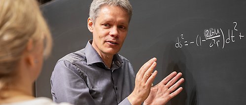 Ulf Danielsson gestikulerar framför svart tavla med ekvation.