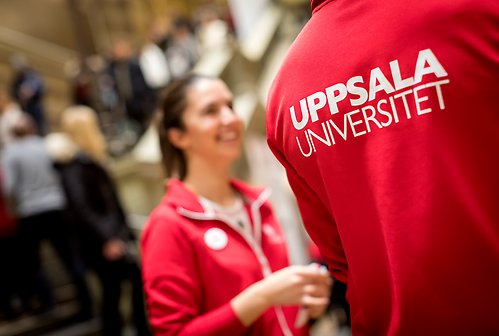 Två studenter, en med Uppsala Universitet på ryggen