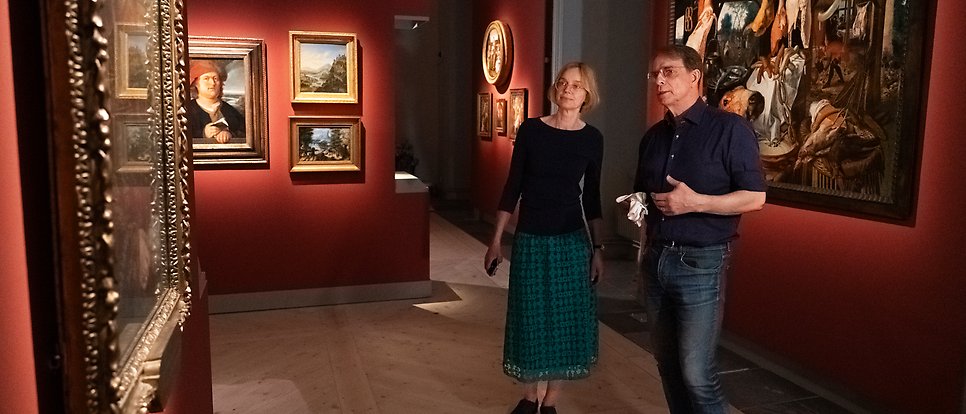 Cecilia and Mikael are standing in the hall completely surrounded by art on the walls.