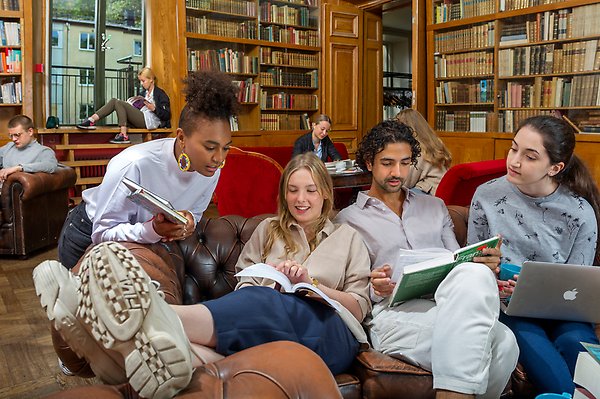 Students sitting together on a sofa looking through books