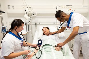 Läkarutbildning, två studenter står vid en säng där i en patient ligger, blodtryck mäts